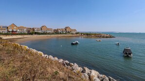 Uma área residencial costeira com casas, uma praia de areia e águas calmas com barcos.