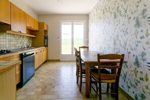 Una cucina con mobili in legno, zoccolo a piastrelle e un tavolo da pranzo con sedie.