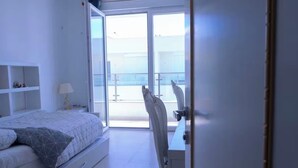Quarto com cama, escrivaninha e vista para o exterior.