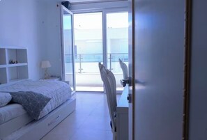 Ein Schlafzimmer mit Bett, Schreibtisch und Blick ins Freie.