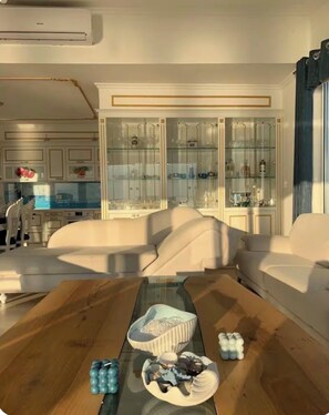 A modern living room with a glass coffee table, white sofas, and a glass cabinet with decorative items. -     Beautiful Apartment Near the Beach with Spectacular Sunset ViewsShëngjin (Shëngjin)