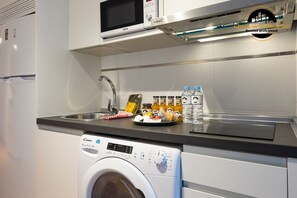 A compact kitchen with a microwave, a water dispenser, and a washing machine. - Apartment 'La Rosaleda' with Balcony, Wi-Fi and Air Conditioning (Málaga)