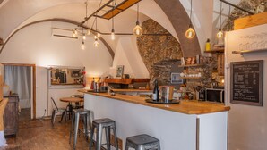 Eine rustikale Bar mit einer Steinwand, einer Holztheke und hängenden Glühbirnen.