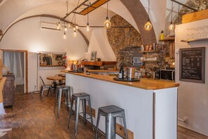A rustic bar area with a stone wall, wooden counter, and hanging light bulbs. - Le Loft de L'Île - A 250m de la Plage (L'Île-Rousse)