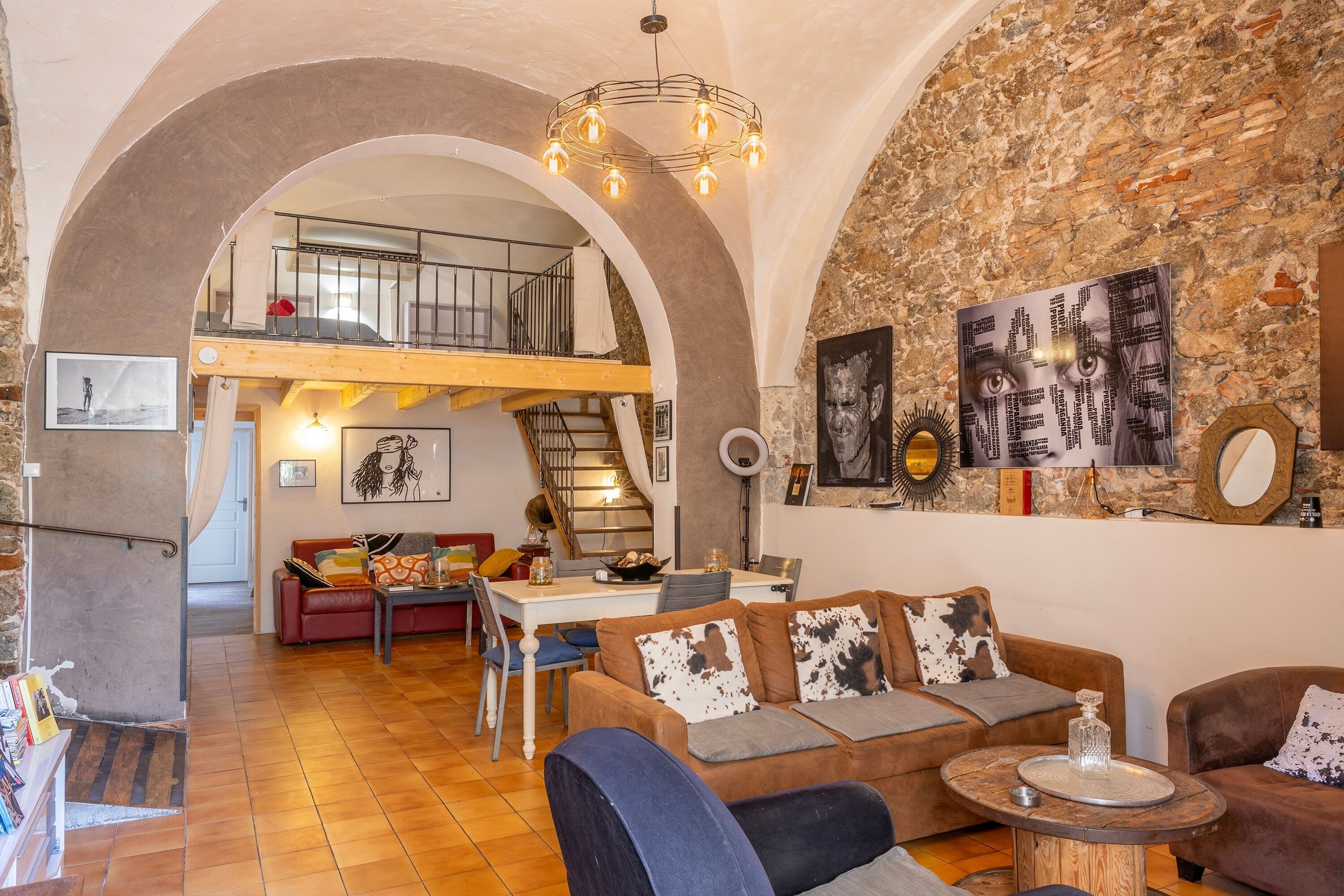 Un loft espacioso con techo alto, paredes de ladrillo visto y un nivel entre piso.