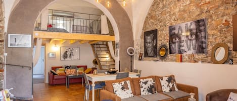 Un loft espacioso con techo alto, paredes de ladrillo visto y un nivel entre piso.