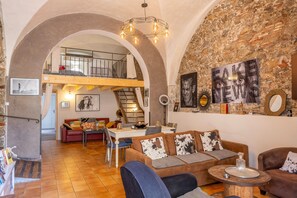 A spacious loft with a high ceiling, exposed brick walls, and a mezzanine level. - Le Loft de L'Île - A 250m de la Plage (L'Île-Rousse)