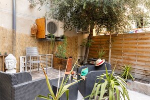 A patio area with outdoor furniture, a Buddha statue, and potted plants. - Le Loft de L'Île - A 250m de la Plage (L'Île-Rousse)