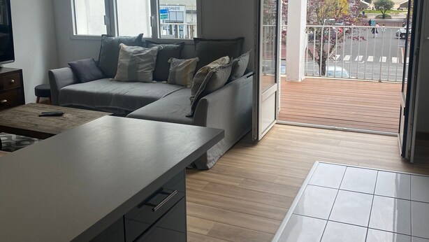 Ein modernes Wohnzimmer mit Sofa, Couchtisch und Küchenzeile inklusive Spüle und Schränken.