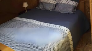 Ein Schlafzimmer mit Oberlicht, einem Bett mit gemusterten Textilien und einem Schild, das Neoprenanzüge bewirbt.