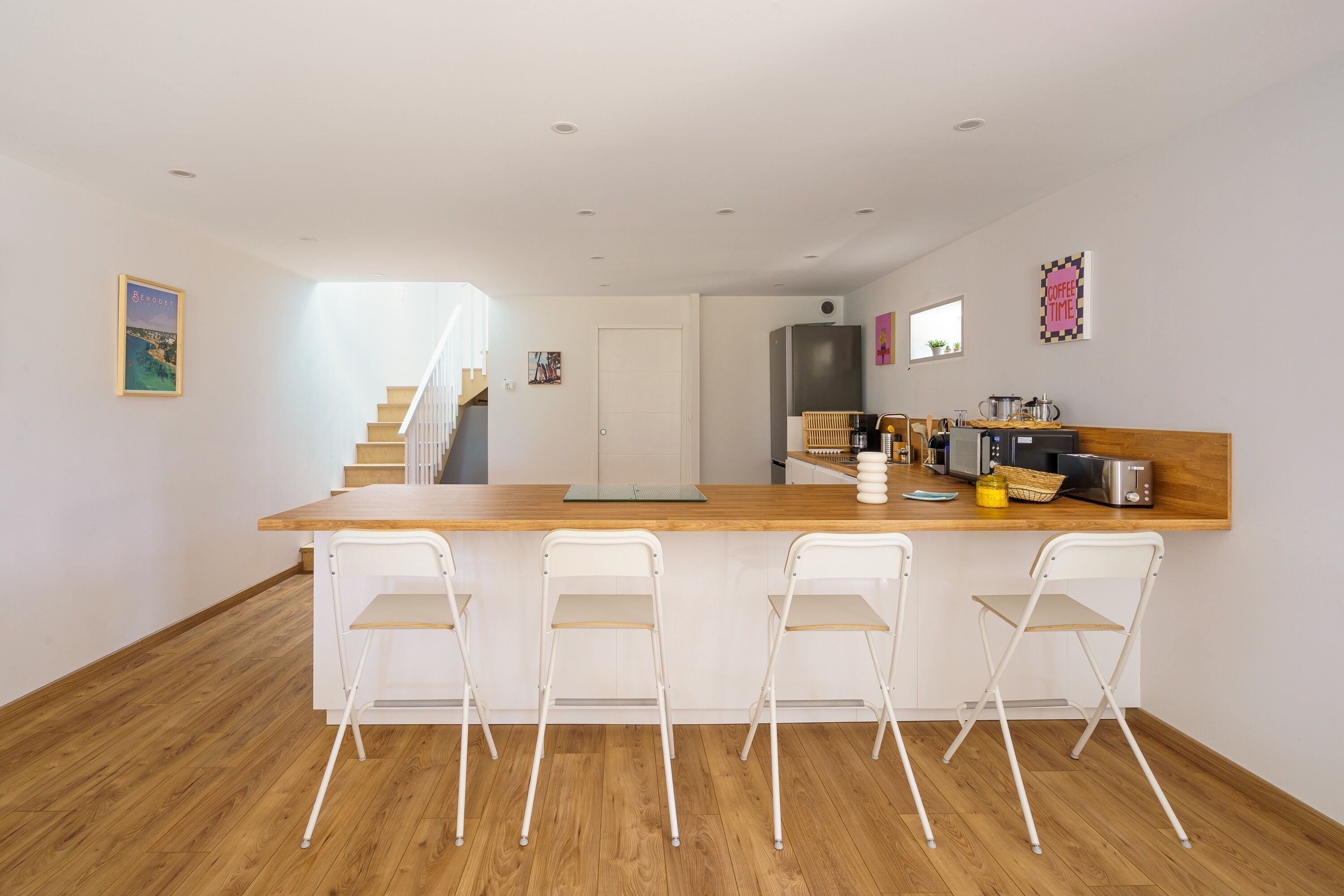 A modern kitchen with a wooden countertop, white chairs, and a built-in oven.