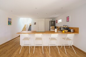 Eine moderne Küche mit einer Holz Arbeitsplatte, weißen Stühlen und einem eingebauten Backofen.
