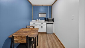 Een kleine keuken met een houten tafel, witte kastjes, een magnetron en een vaatwasser.