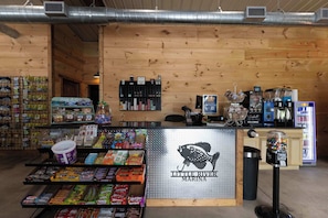 Un kiosque proposant des collations et des boissons, avec un assortiment de produits, un distributeur automatique et une enseigne indiquant « Little River Marina ».