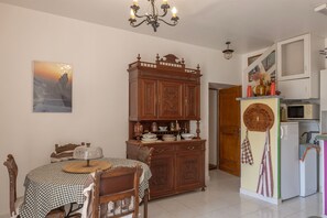 Un coin repas avec une nappe à carreaux, des chaises en bois, un meuble décoratif et un tableau accroché au mur.
