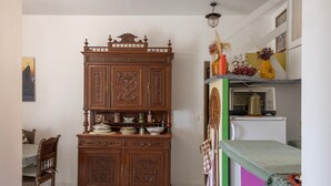 Una cocina con un mueble de madera, una mesa de comedor con sillas y un refrigerador.