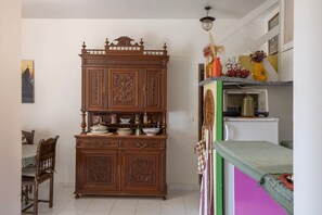 A kitchen with a wooden cabinet, a dining table with chairs, and a refrigerator. - Le Refuge d'U Casone - Balcon avec jolie vue (Crocicchia)