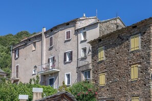 A multi-story building with stone and plaster exteriors, balconies, and windows with shutters. - Le Refuge d'U Casone - Balcon avec jolie vue (Crocicchia)