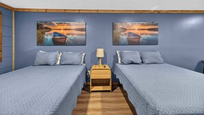 Un dormitorio con dos camas, una mesita de noche y dos cuadros de un atardecer sobre un lago.