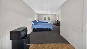 Quarto de hotel com uma cama, uma mesa, uma cadeira e uma televisão.