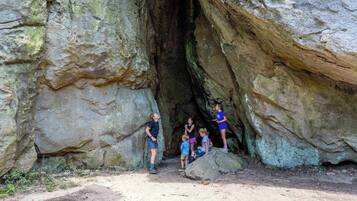 Un grupo de personas frente a una gran formación rocosa con una abertura parecida a una cueva.