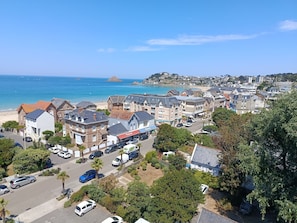 Eine Küstenstadt mit Wohnhäusern, Geschäftsgebäuden, einem Strand und einem wolkenlosen Himmel.