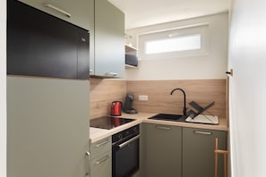 Eine kleine Küche mit Geschirrspüler, Backofen und Spüle mit modernem Wasserhahn.