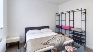 Una camera da letto con un letto, una panca, un letto a castello e un mobile contenitore.