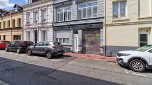 Una vista di una strada con auto parcheggiate, un edificio con un basculante e cielo sereno.