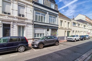 Une rue bordée de voitures garées et de bâtiments à l’architecture européenne traditionnelle.