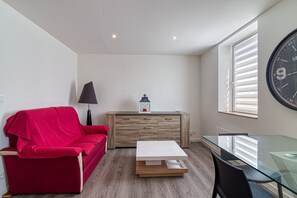 Ein modernes Wohnzimmer mit einem roten Sofa, einem Glastisch und einem Holzschrank.