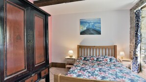 Ein Schlafzimmer mit einem Holzbett, einem Nachttisch mit Lampe, einem großen Kleiderschrank und einem Gemälde an der Wand.