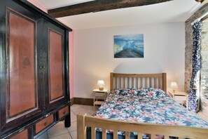Ein Schlafzimmer mit einem Holzbett, einem Nachttisch mit Lampe, einem großen Kleiderschrank und einem Gemälde an der Wand.