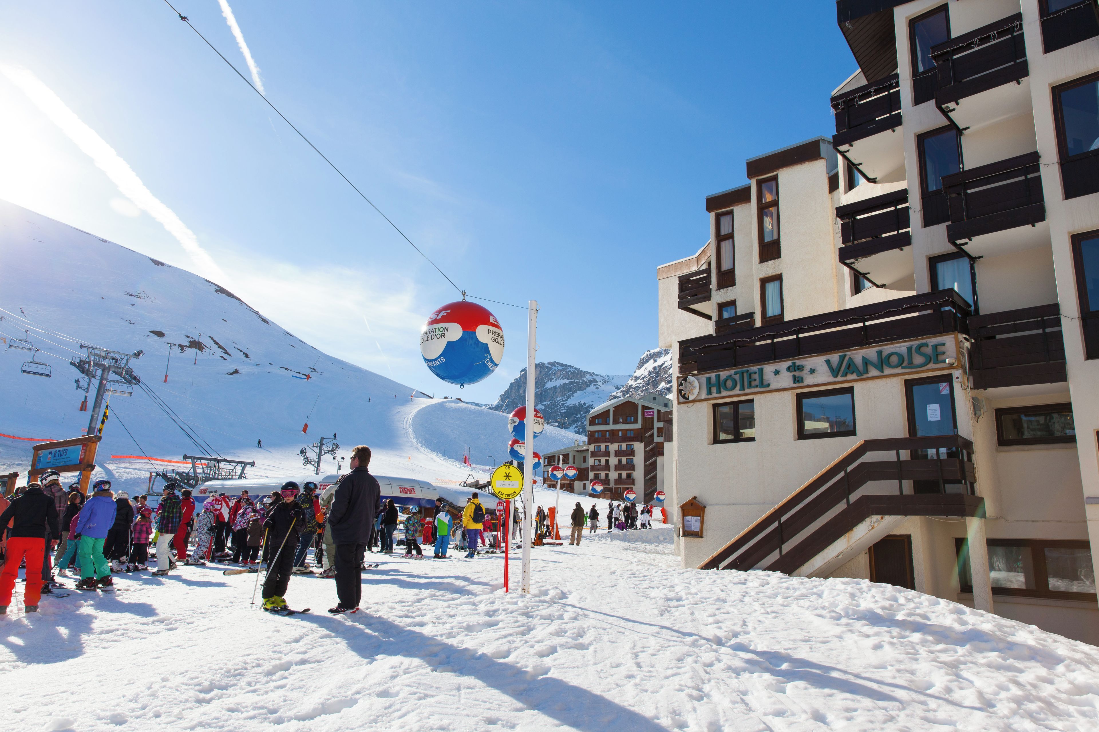 Un hôtel avec une enseigne indiquant « HÔTEL de la VANOISE », et un télésiège en arrière-plan.