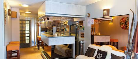 Une pièce comprenant un coin bar, un canapé agrémenté de coussins décoratifs et une horloge murale.