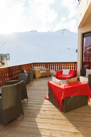 A deck with wicker furniture and red cushions, overlooking a snowy mountain. - Hôtel La Vanoise (Tignes)