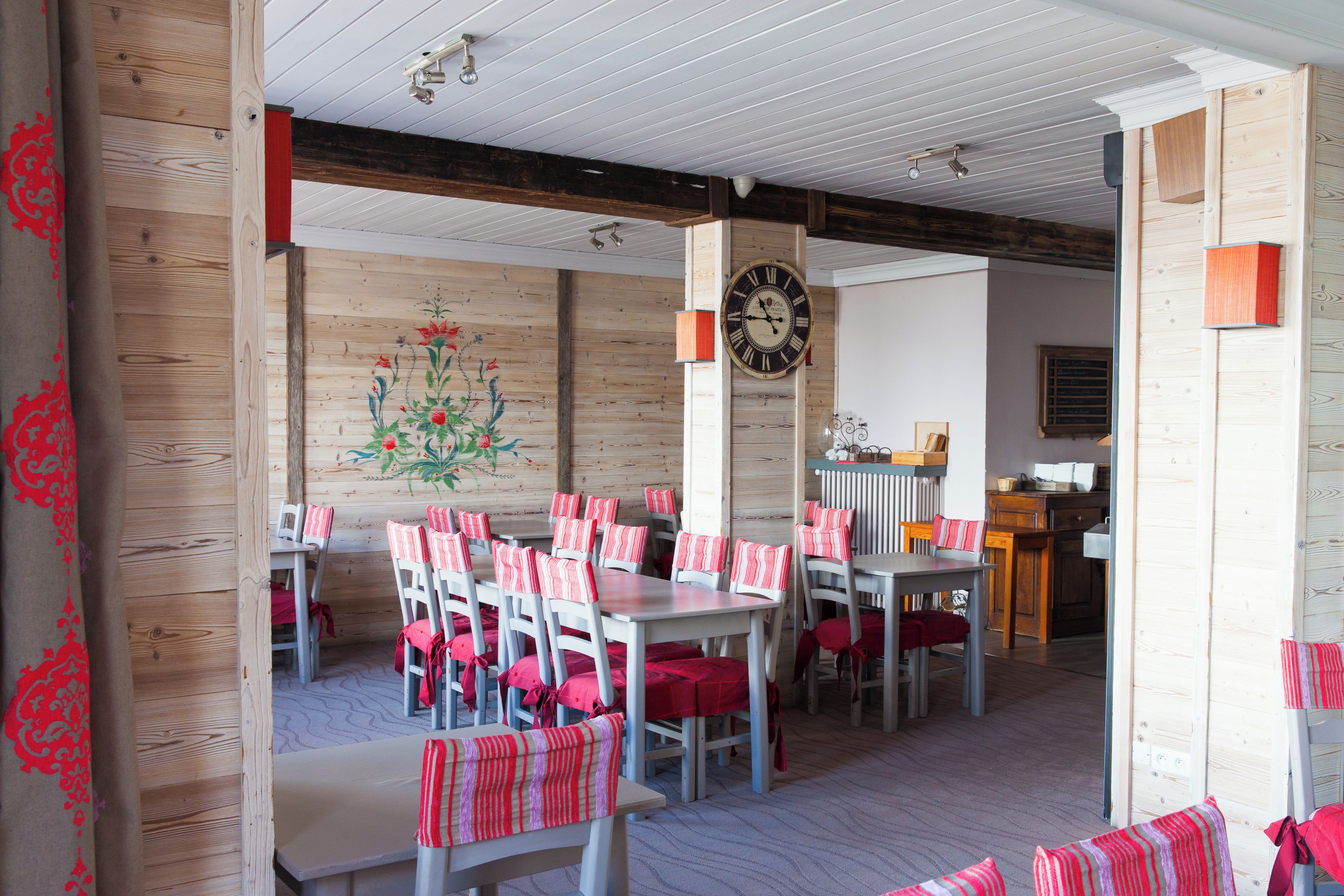 A restaurant with wooden walls, a floral mural, and tables with striped cushions.