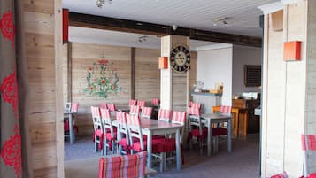 A restaurant with wooden walls, a floral mural, and tables with striped cushions.
