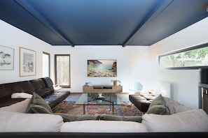 Ein modernes Wohnzimmer mit einem Glastisch, Ledersofas und einem großen Gemälde mit einer Strandansicht.