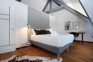 Een slaapkamer met een bed, een bureau en een stoel. Er is een kledingkast en een vachttapijt.