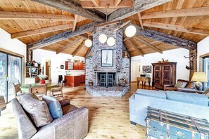 A spacious living area with a stone fireplace, wooden beams, and a large sofa.