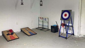 Ein Zimmer mit Dartscheibe, Zielscheibe und einem kleinen Tisch mit einem Gesellschaftsspiel.