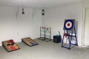 Ein Zimmer mit Dartscheibe, Zielscheibe und einem kleinen Tisch mit einem Gesellschaftsspiel.