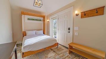 Une chambre à coucher comprenant un lit, un banc, une porte et une étagère fixée au mur.