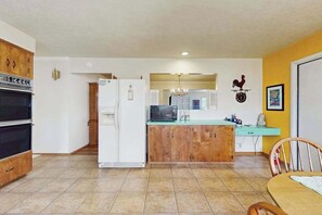 Una cocina con refrigerador, microondas y armarios de madera.