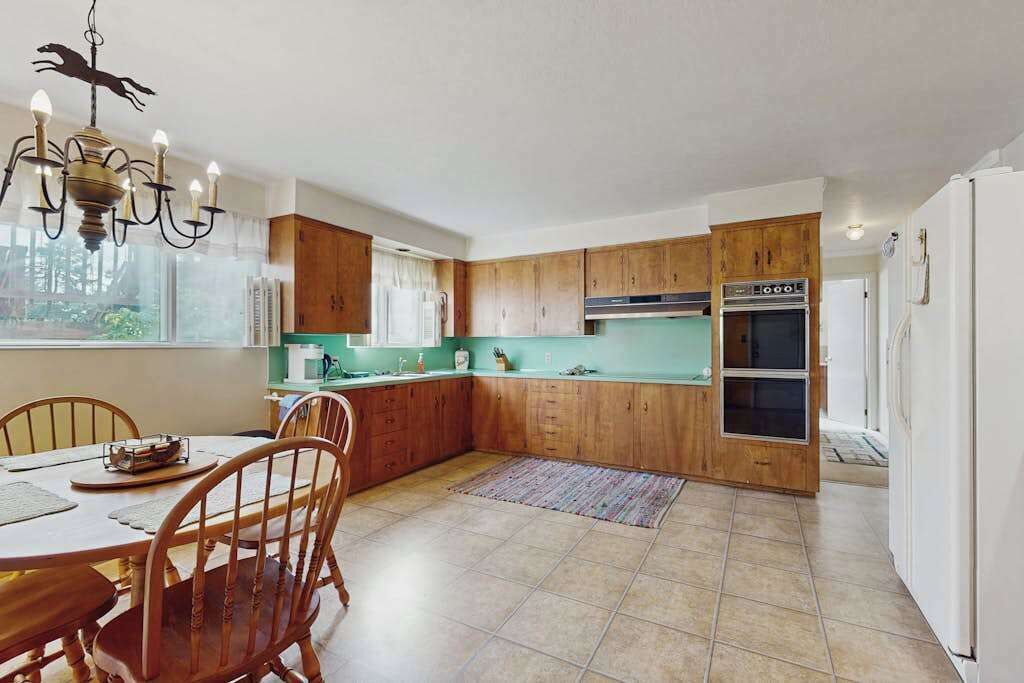 A kitchen with wooden cabinets, a built-in oven, and a dining area with a table and chairs.