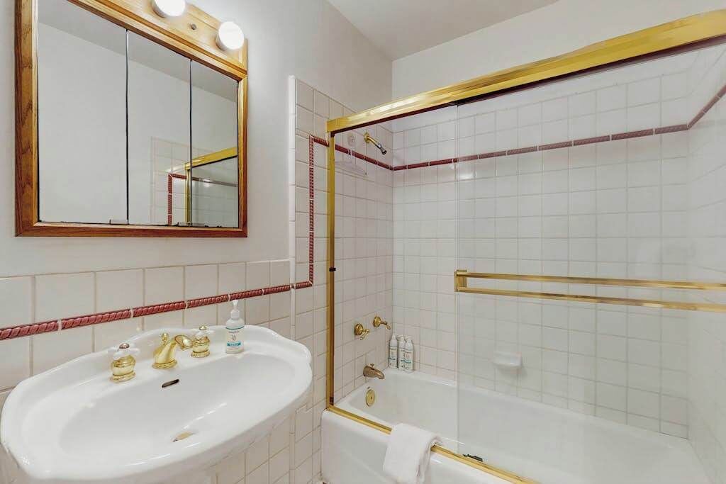 A bathroom with a white sink, a mirror, and a bathtub.