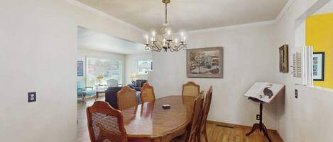 Un comedor con una mesa y sillas de madera, una lámpara de araña y un cuadro en la pared.