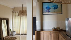 Uma cozinha moderna com armários de madeira, uma geladeira de aço inoxidável e uma pintura grande na parede.