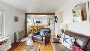 A living room with a leather sofa, a coffee table, and a dining area with wooden chairs. - Seascape Home - Spacious Coastal Retreat with Ocean Views (Trinidad)